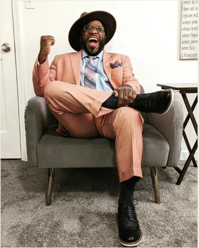 Bakari Holmes, in a pink suit, mid-laugh